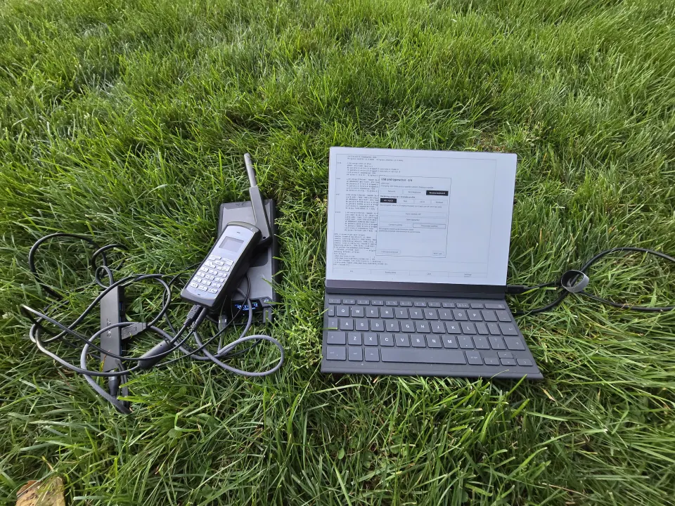My reMarkable 2 running Inkline on the grass, beside the GSP-1700, power bank, powered USB hub, and cables.